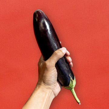 hand holding an eggplant against a red background