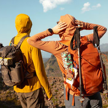 Two hikers in outdoor gear overlooking a scenic landscape.