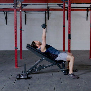 person performing a dumbbell exercise on an adjustable bench in a gym